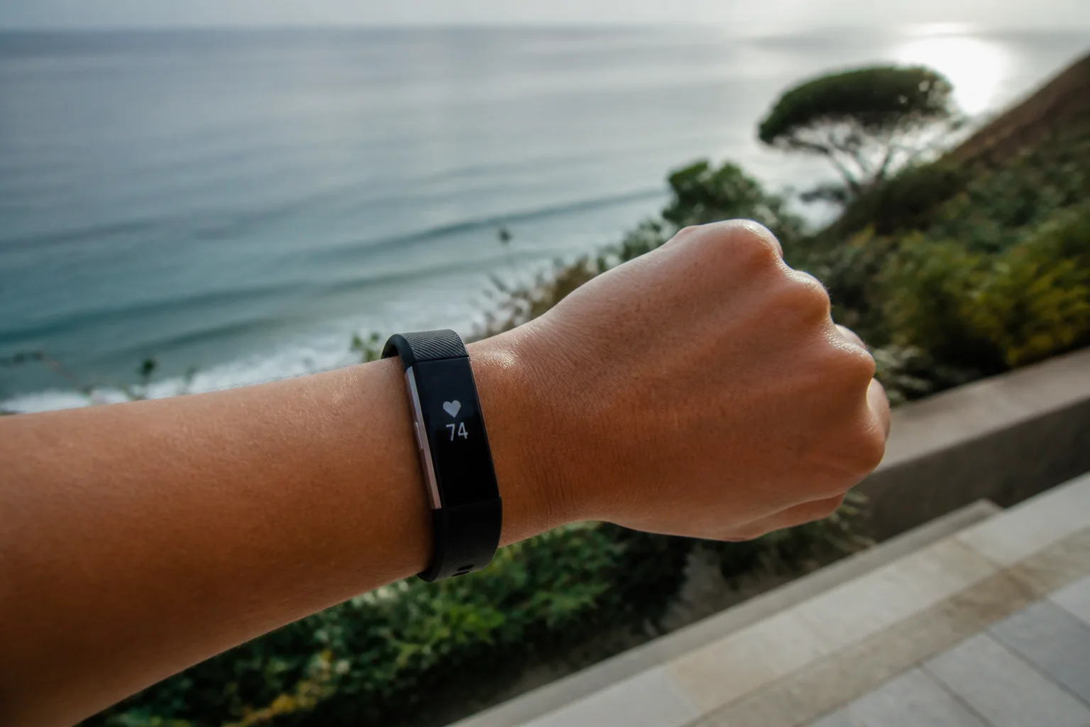 佩戴在手腕上的 Fitbit Alta HR,屏幕显示心率 74