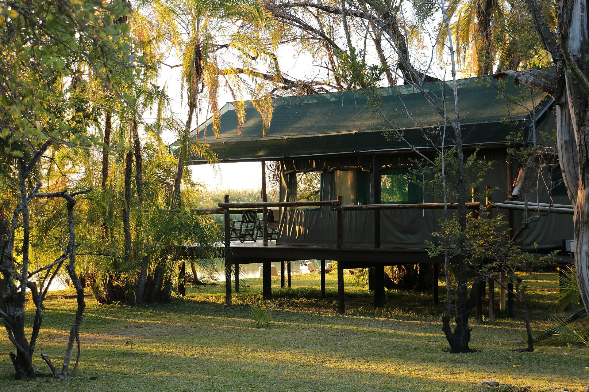 Erhöhte Zeltlodge zwischen Palmen und Bäumen im Okavango-Delta