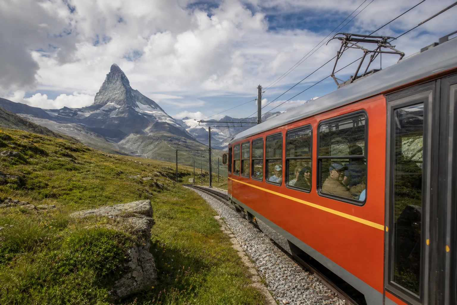 Rote Zahnradbahn vor einem markanten Schweizer Alpengipfel im Sommer
