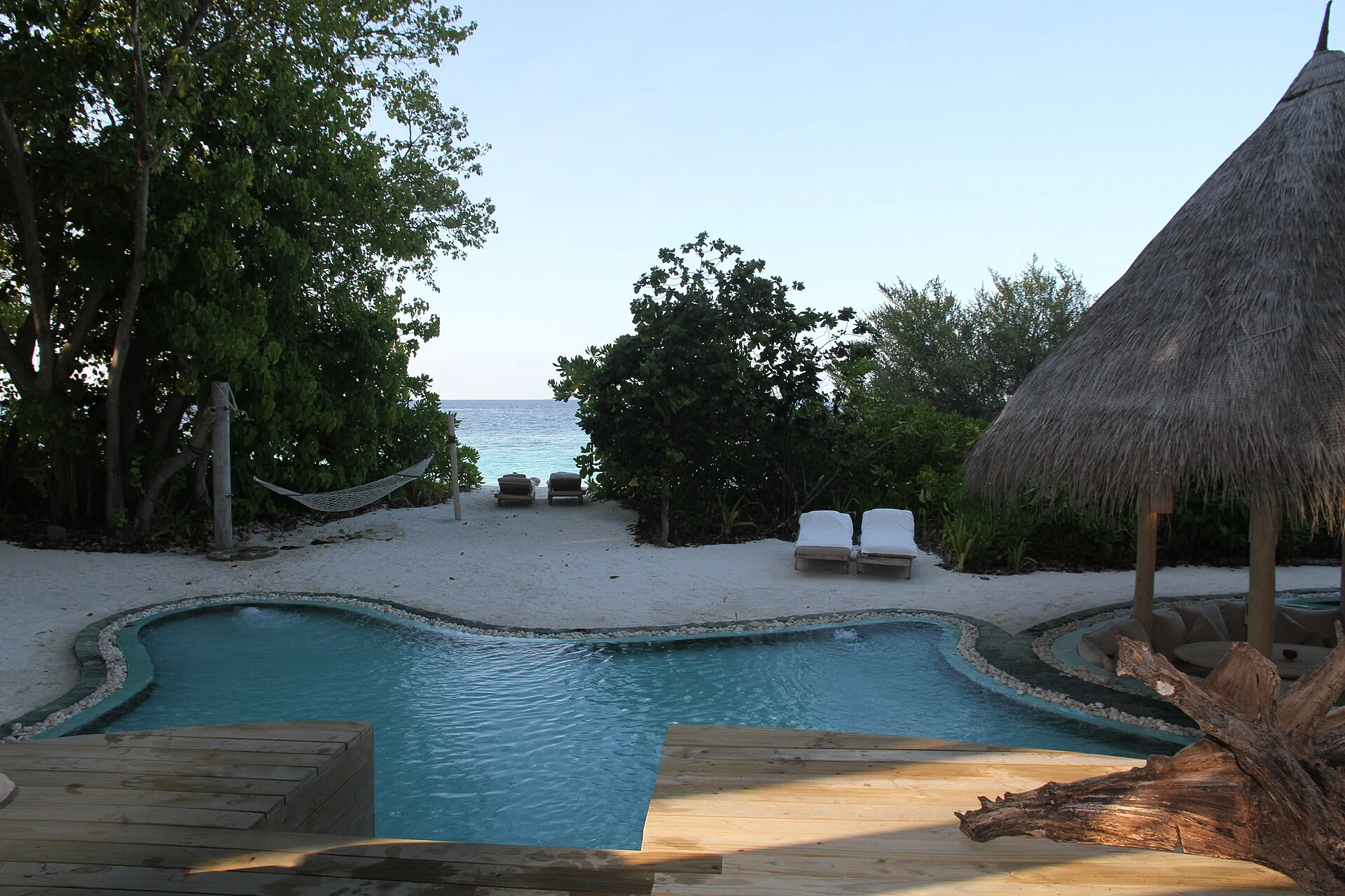 Island-resort pool in Baa Atoll between vegetation, sand and sea