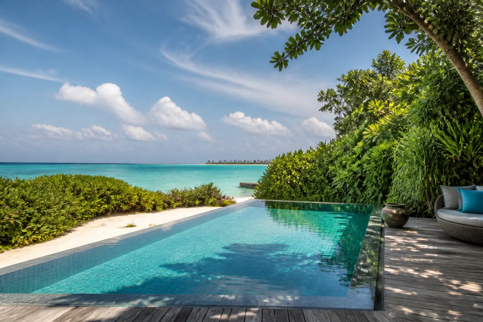Island-resort pool in Baa Atoll between vegetation, sand and sea