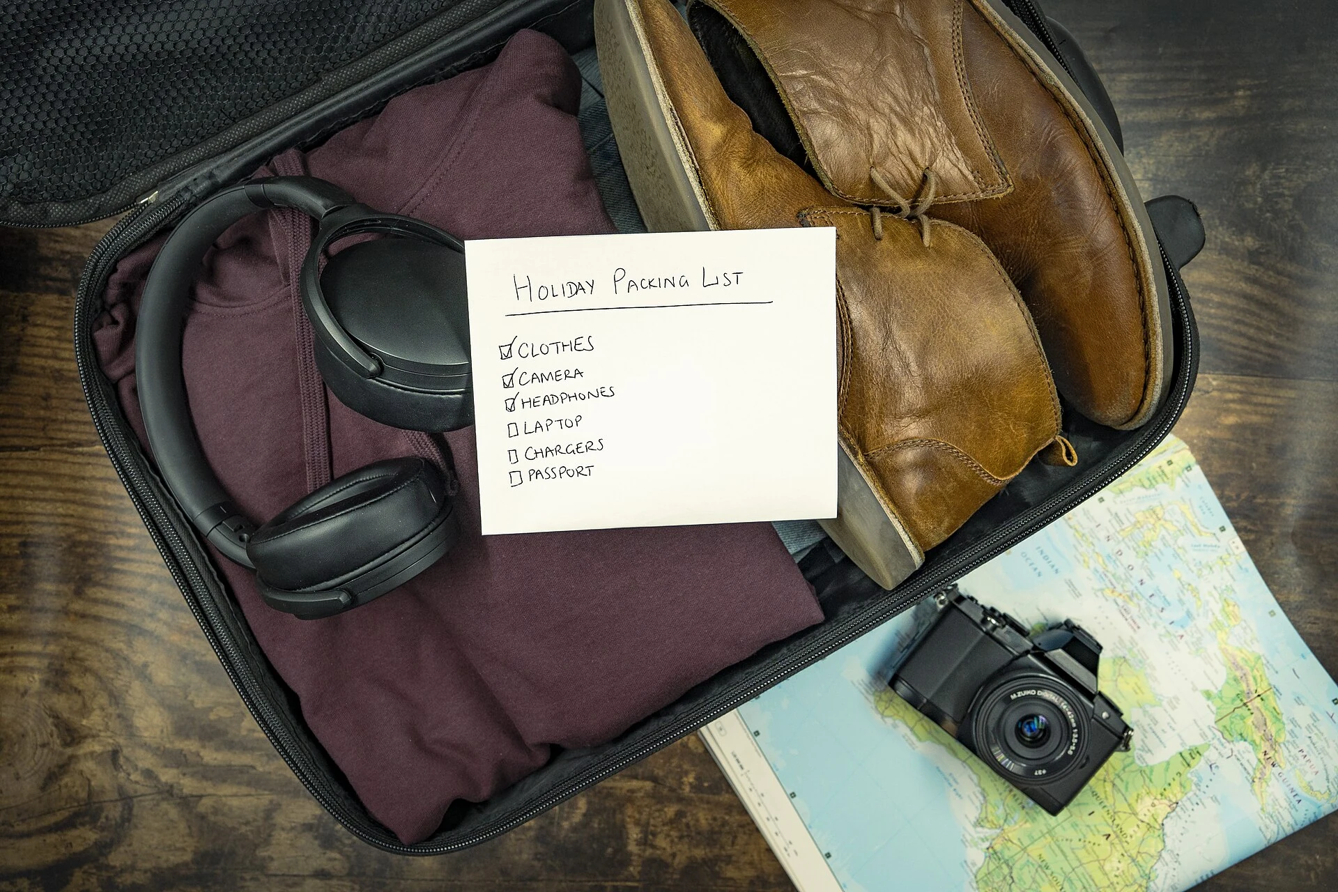 Open travel bag with clothing, shoes, camera and packing list