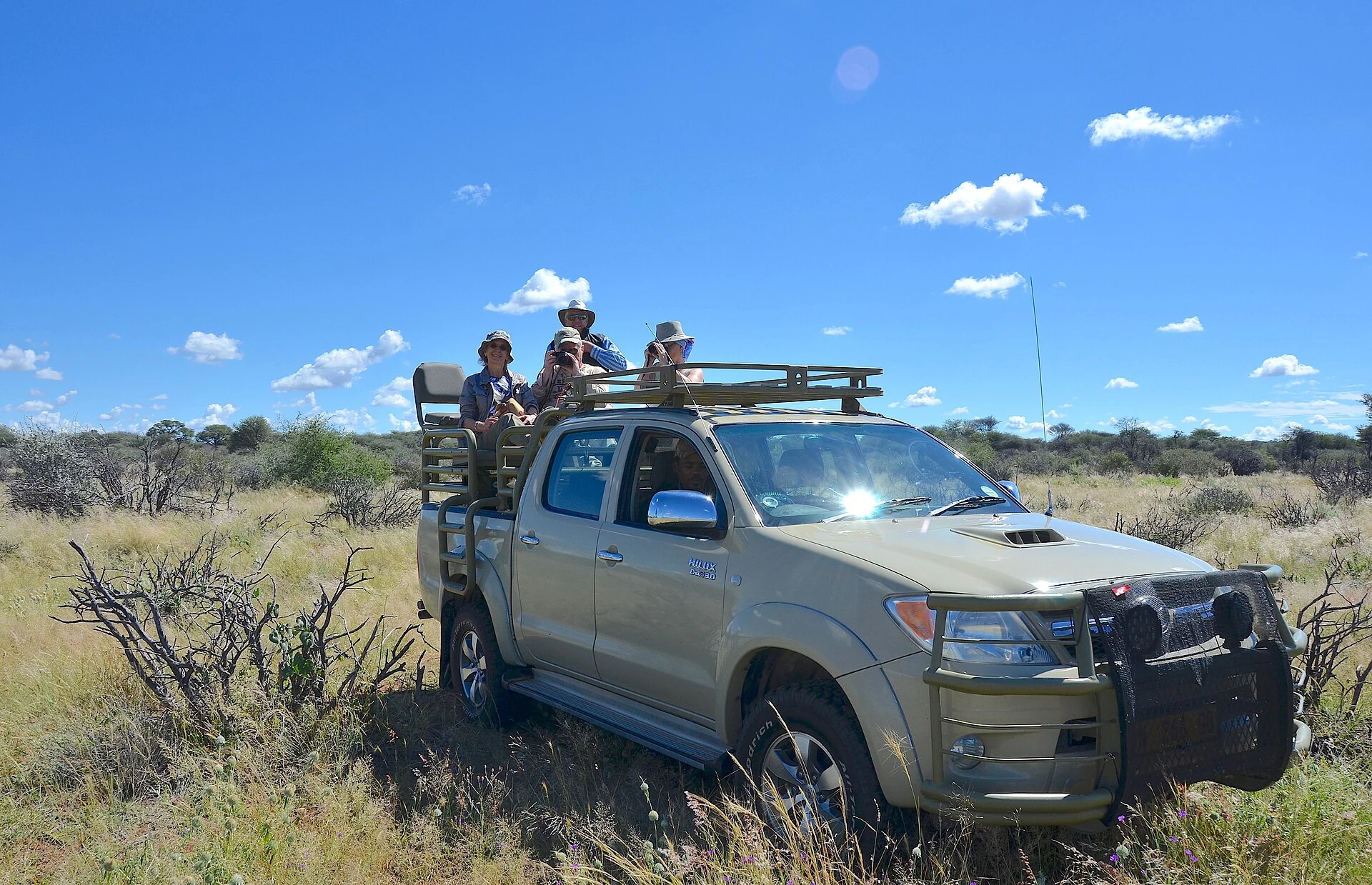 Open game-drive vehicle with raised seating and photographing guests in Namibia