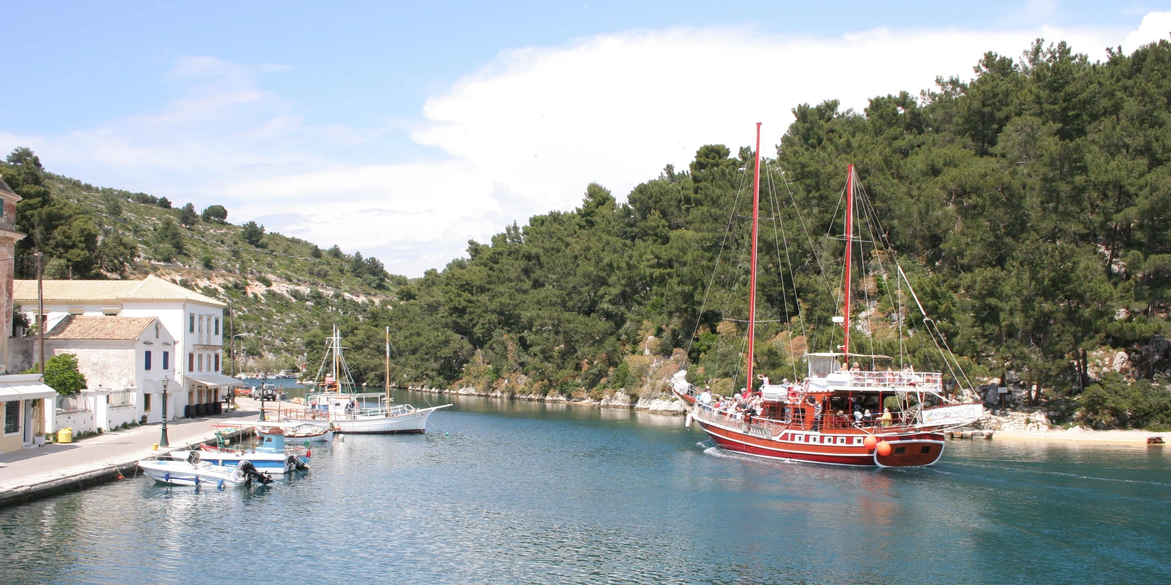 Boats against the green sheltered shoreline in Gaios harbour on Paxos
