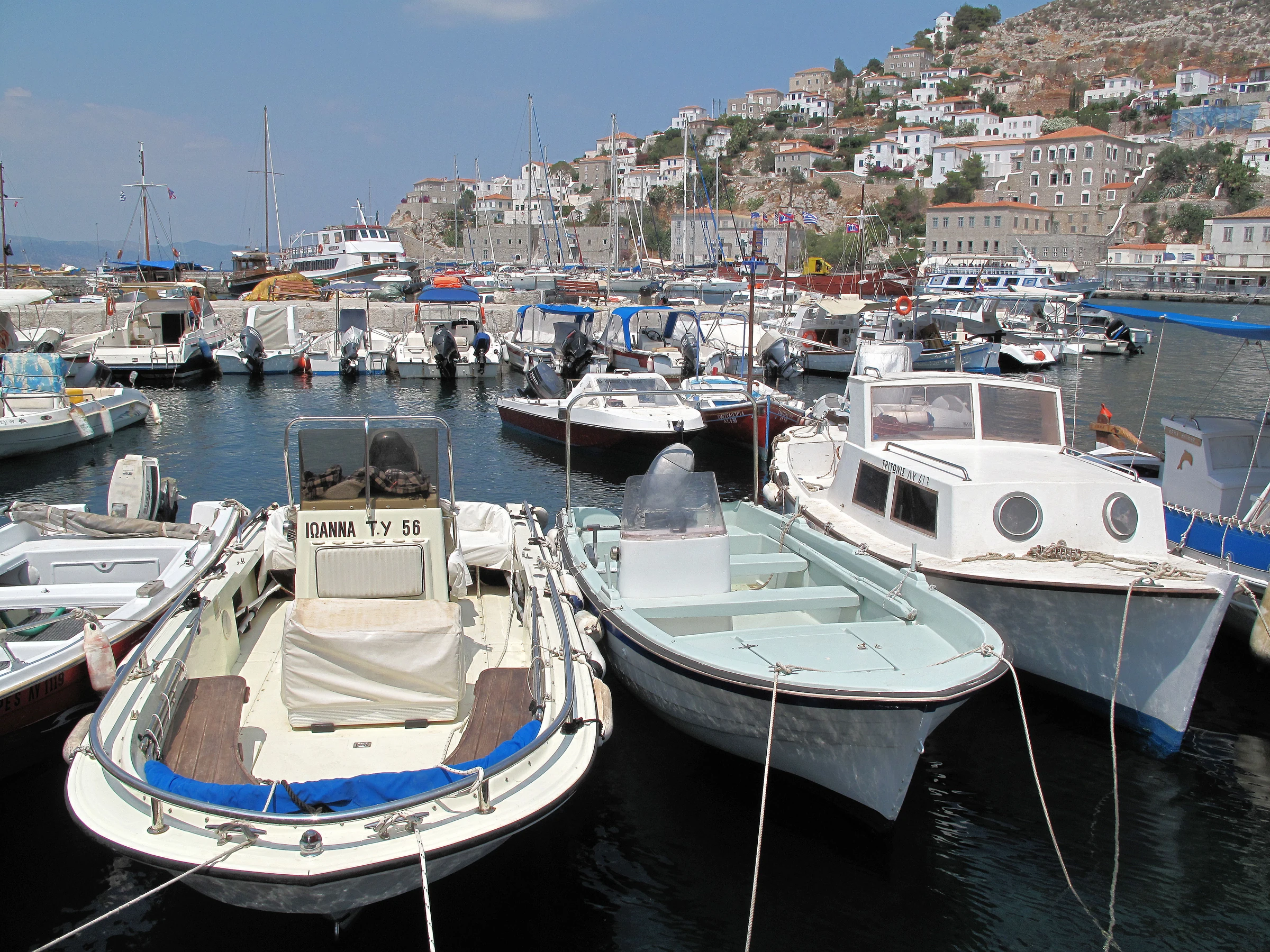 Crowded Hydra harbour with leisure and working boats below the hillside town