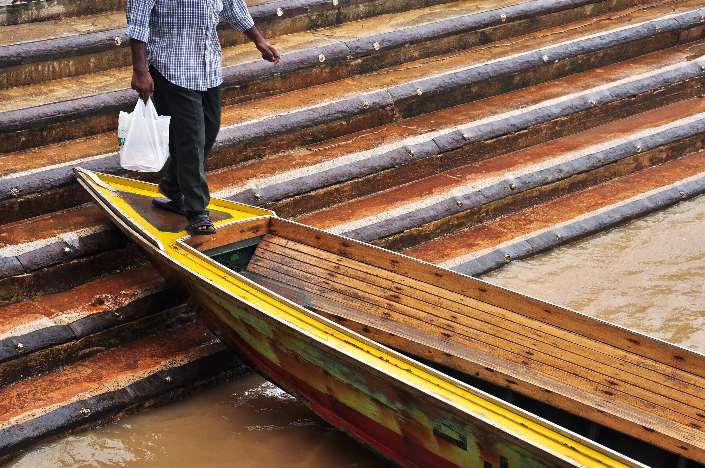Passagier beim Einstieg in ein Wassertaxi an einer nassen Stufenanlegestelle in Brunei