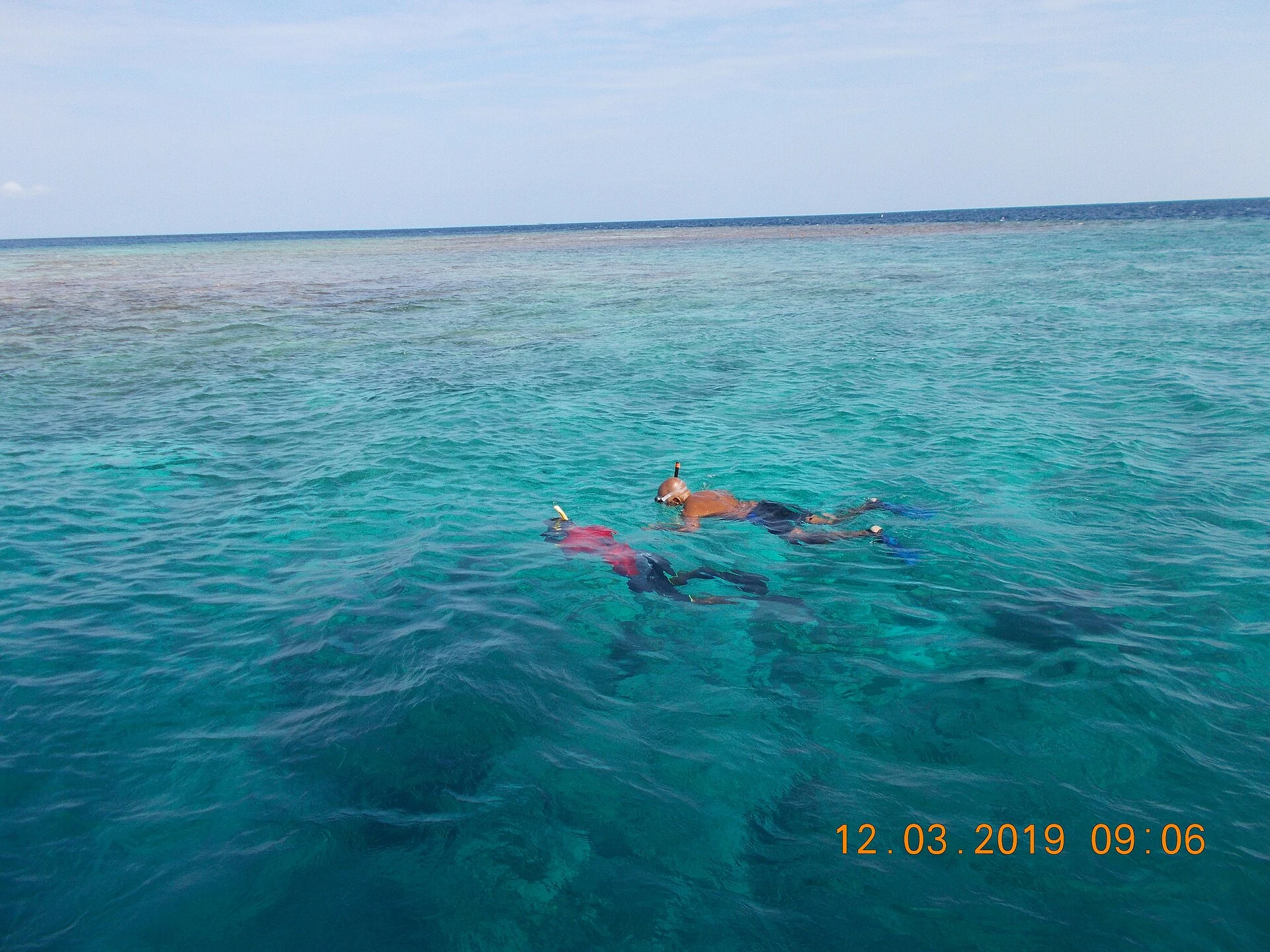 Two snorkellers with a guide over the reef shelf at Hangnaameedhoo in the Maldives