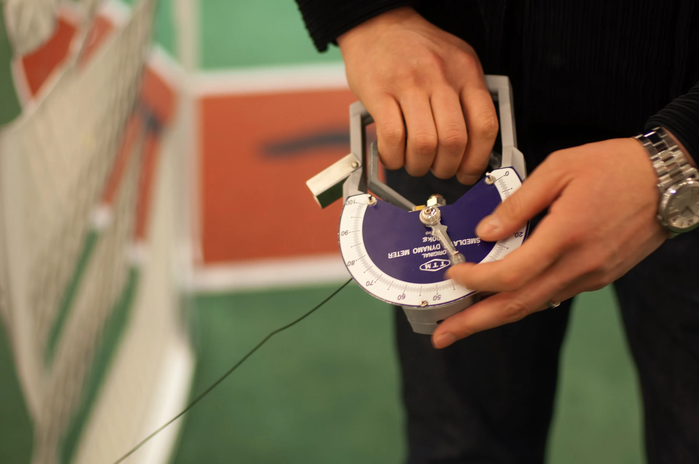 Hand hält einen mechanischen Dynamometer bei einer Griffkraftmessung