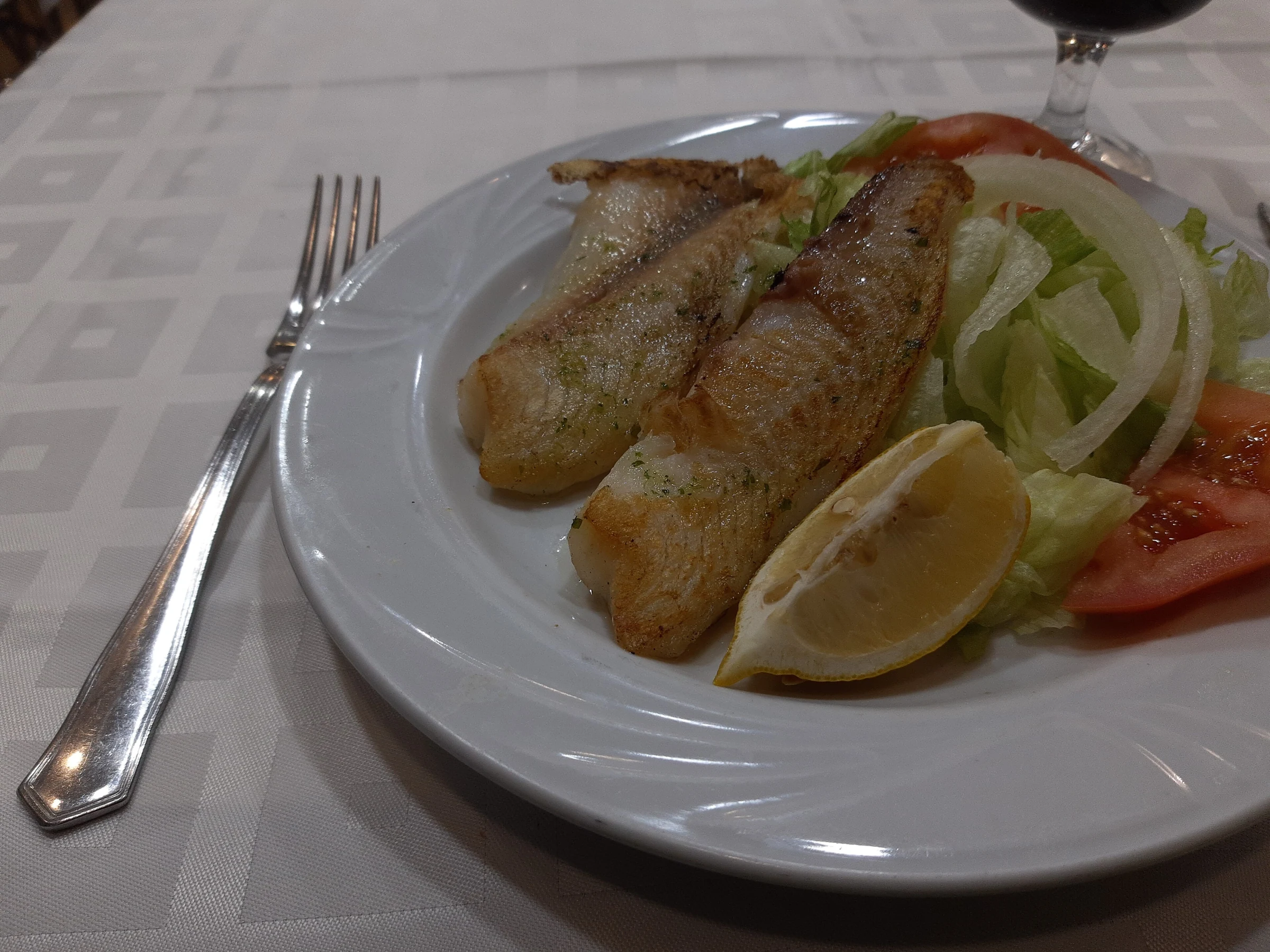 Poisson grillé avec salade composée servi dans une assiette à Madrid