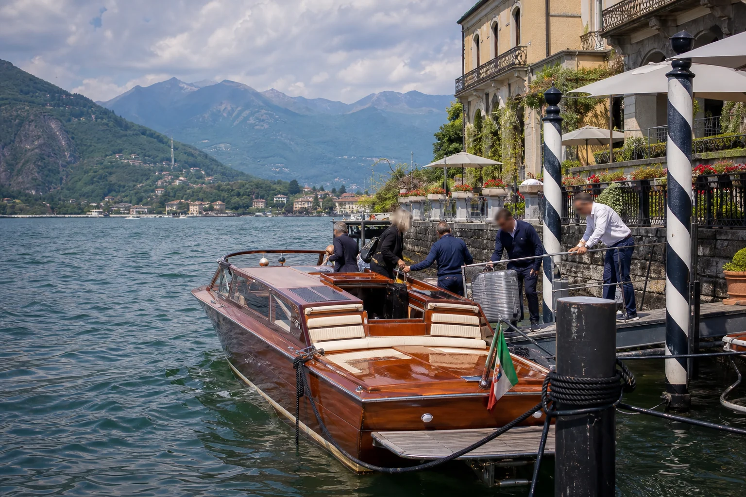 Arrivée coordonnée en bateau en bois avec bagages à un ponton d’hôtel fictif du lac de Côme