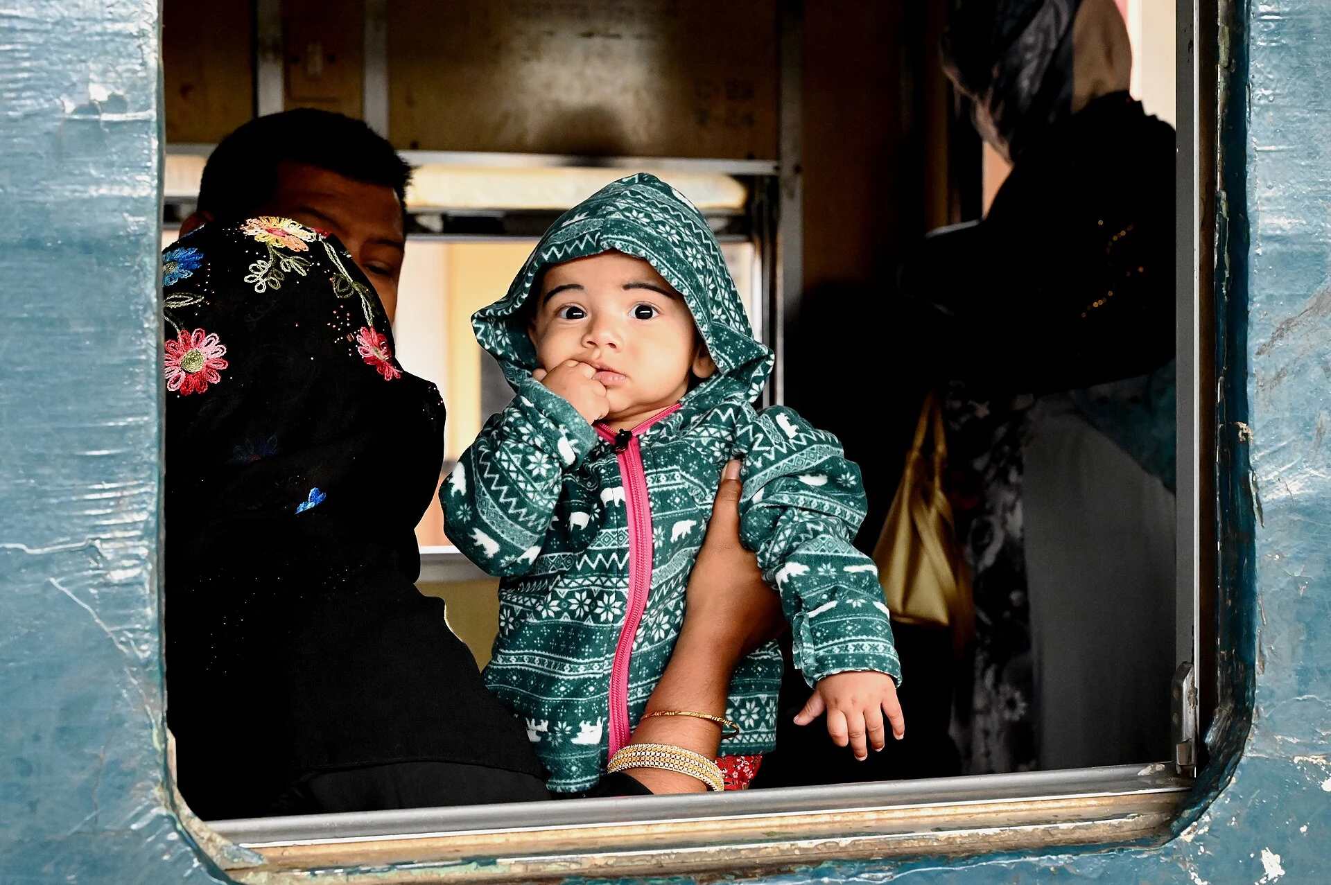 Infant held by an adult at a train window during a real family rail journey