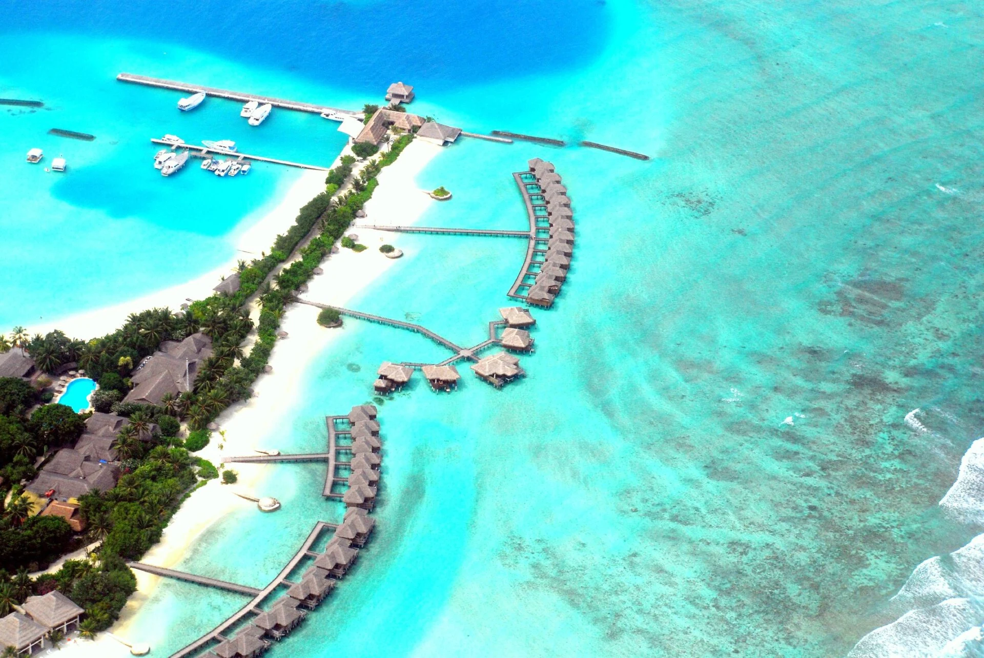Aerial view of the real Full Moon Maldives resort with villas, marina, lagoon and reef
