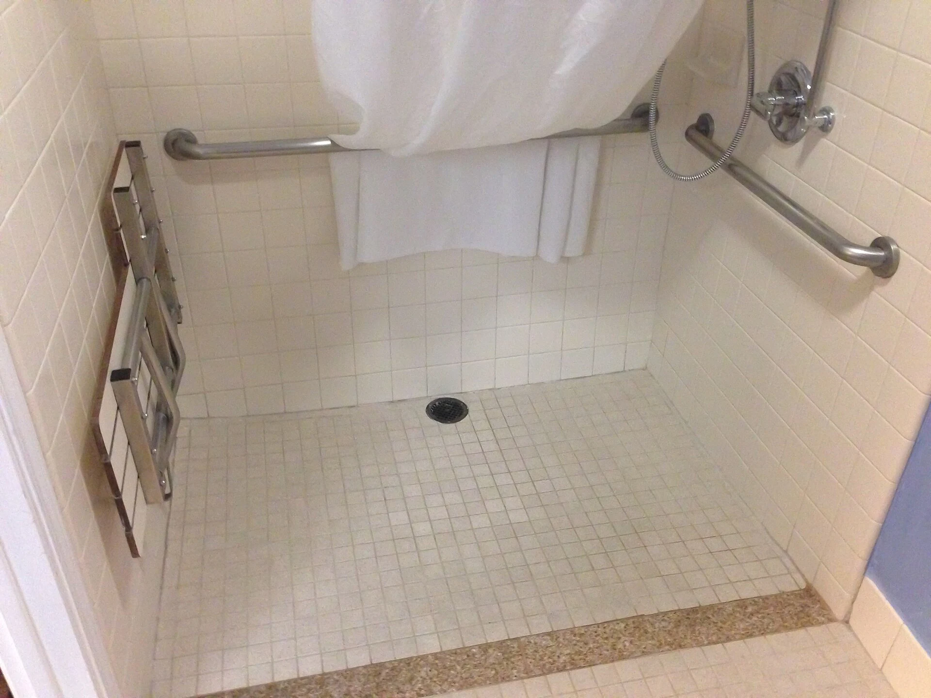 Real accessible hotel shower with grab rails and folding seat