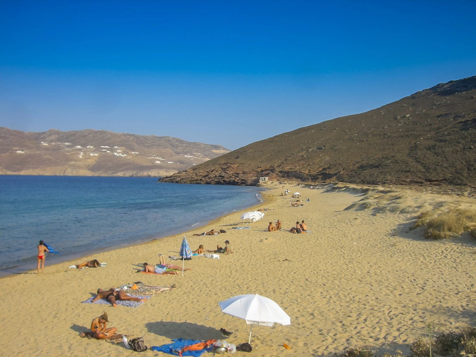 Real sandy Mykonos beach with bathers and an open bay