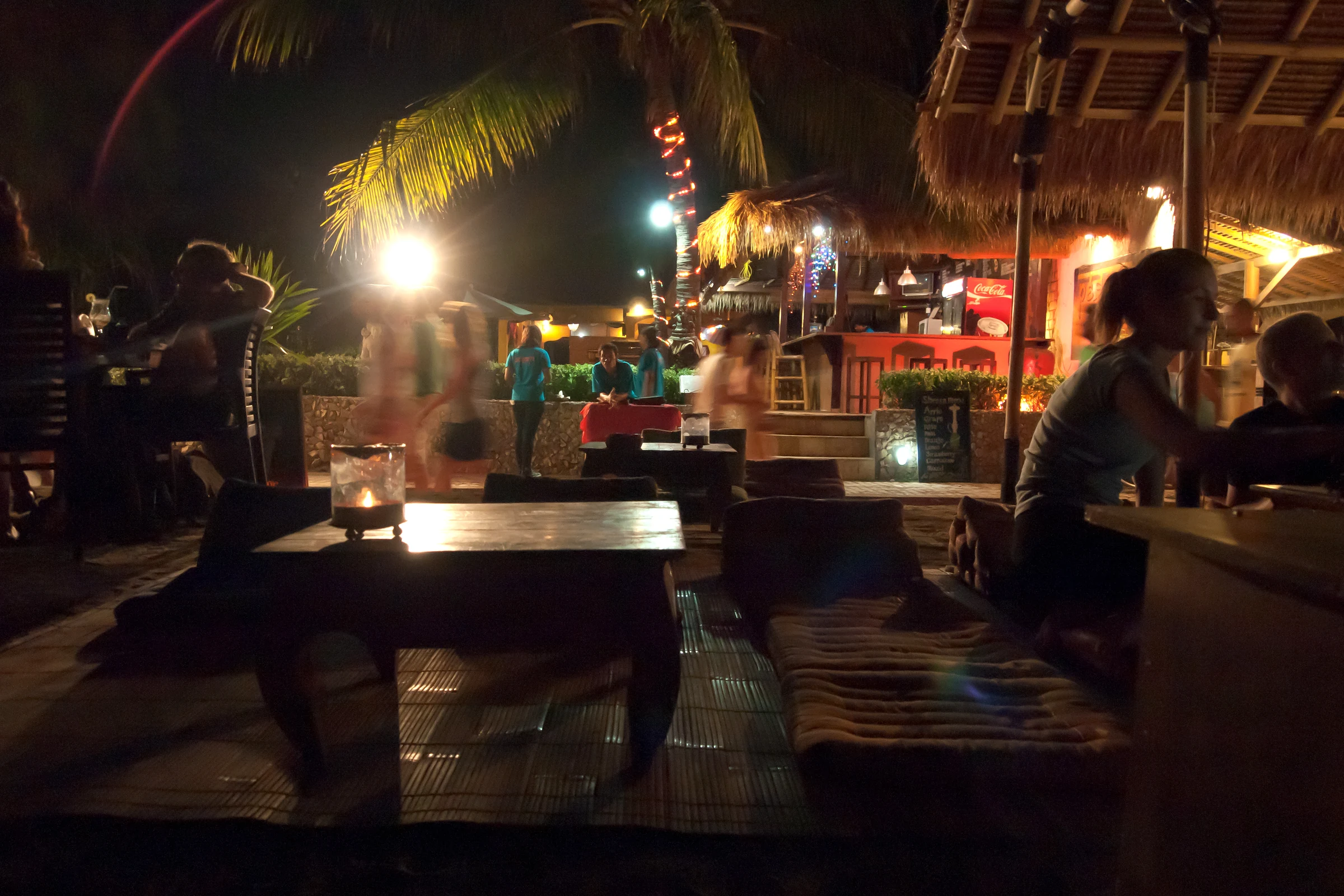 Nächtliches Strandrestaurant mit niedrigen Tischen und Palmdächern auf Gili Trawangan