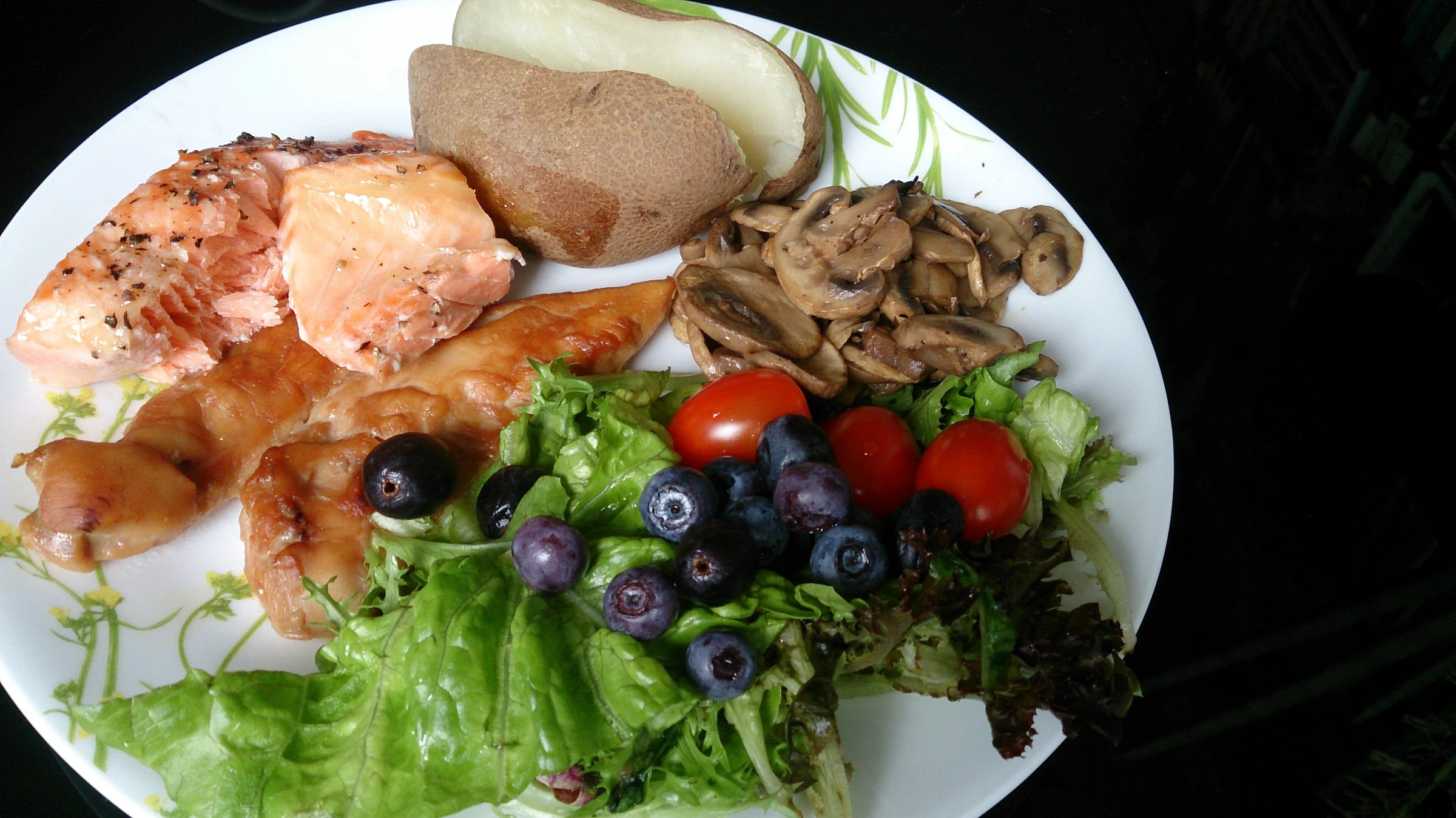 Meal with salmon, mushrooms, potato, salad, tomatoes and blueberries